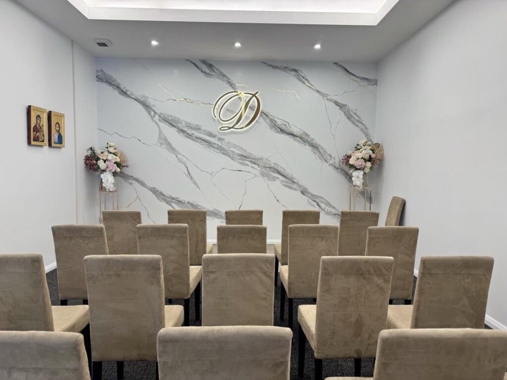 Rear view inside Divine Family Funerals' chapel showing the orderly arrangement of chairs and the altar in the distance