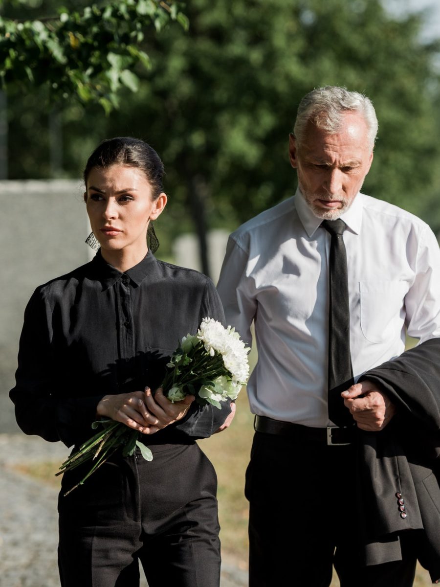 handsome-senior-man-standing-with-attractive-woman-holding-flowers-on-funeral.jpg